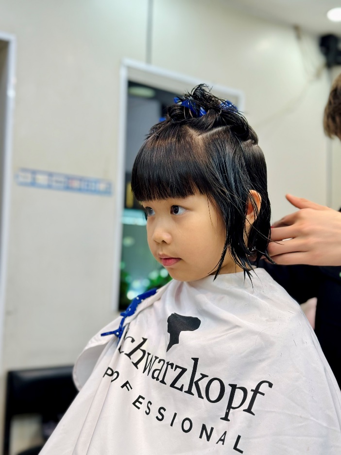 A young child getting her hair cut

Description automatically generated