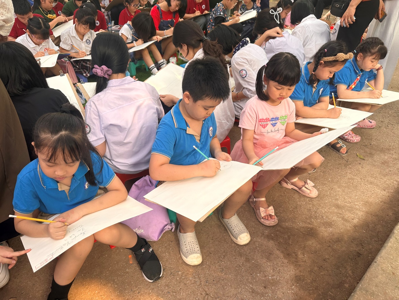 A group of children sitting on the ground writing on paper

Description automatically generated